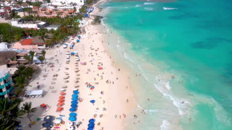 Drone-shot-of-Playa-Del-Carmen-coastline-and-resorts-with-people-on-the-beach
