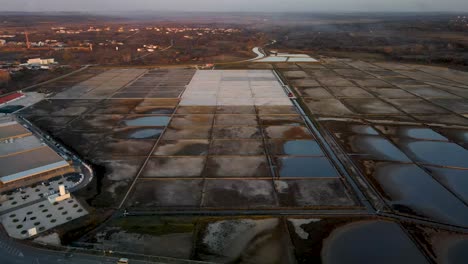 Reverse-drone-flight-next-to-a-salt-field-in-Croatia-in-Nin-town-with-road-and-a-few-cars-at-dusk