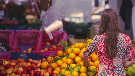 woman-with-brown-hair-going-towards-the-fruit-stand-at-the-fair-to-choose-one-of-them