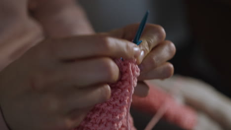 Extreme-close-up-of-woman's-hands-knitting-a-pink-piece-of-clothing