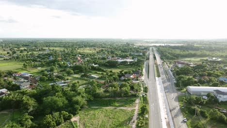 Wild-short-of-aerial-view-railway-crossing-bridge-and-tree-forest-countryside-with-traffic-on-the-road-in-Khonkaen,-Thailand