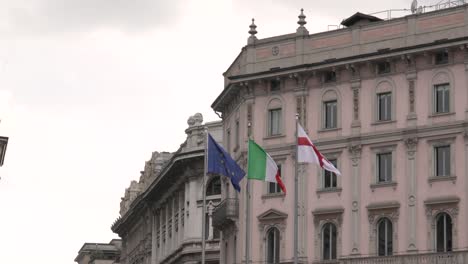 Banderas-Italianas,-Europeas-Y-De-Milán-En-El-Viento-En-El-Antiguo-Palacio-En-El-Centro-De-Milán