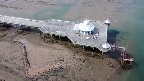 Bangor-seaside-pier-North-Wales-silver-spire-pavilion-low-tide-aerial-view-birdseye-descending-tilt-up