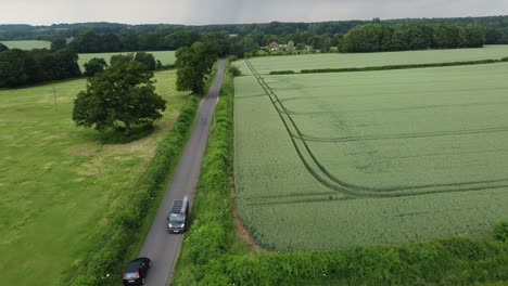 A-drone-following-shot-following-a-very-fast-car-speeding-down-a-quiet-country-lane,having-to-slam-on-the-breaks-to-let-another-car-past,-shot-on-a-very-overcast-and-cloudy-day