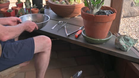 Mann-Fügt-Blumenerde-Zur-Schüssel-Hinzu,-Um-Kaktuspflanzen-Umzutopfen