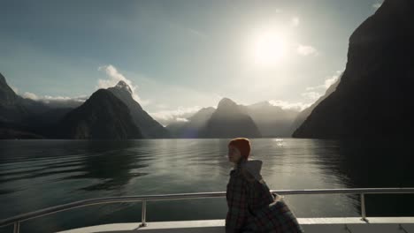 Mädchen-Auf-Einer-Bootsfahrt,-Die-Ein-Malerisches-Bild-Von-Der-Sonne-Macht,-Die-Durch-Steile-Bergwände-Und-Inseln-Im-Neuseeländischen-Milford-Sound-Strahlt