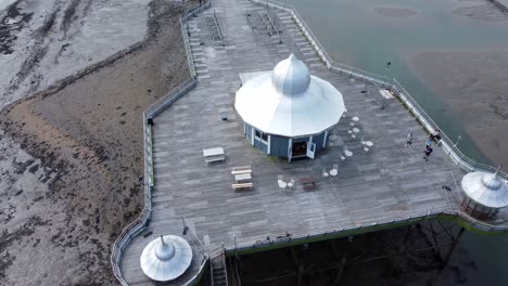Bangor-seaside-pier-North-Wales-silver-spire-pavilion-low-tide-aerial-top-down-orbit-right-view