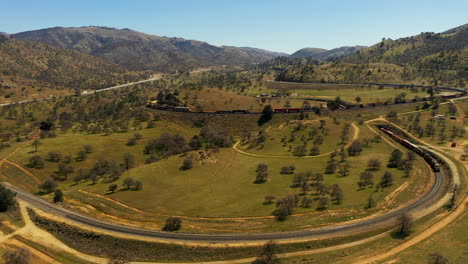 Pull-back-aerial-view-of-a-train-spiraling-through-the-famous-Tehachapi-Loop