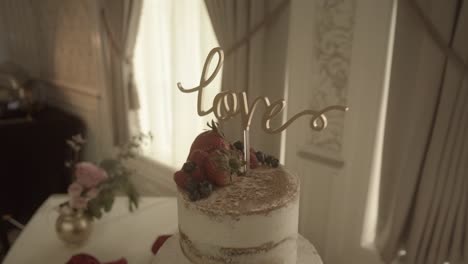 Love-decoration-on-cream-layered-luxury-wedding-cake-centrepiece-at-marriage-banquet-slow-push-in-left