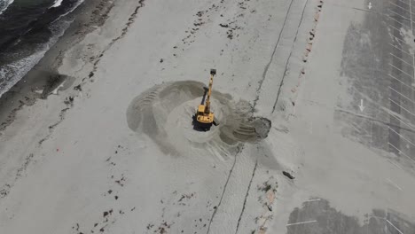 Aerial-drone-birdseye-footage-of-an-excavator-digging-on-Sandy-beach-in-Cohasset,-MA-USA