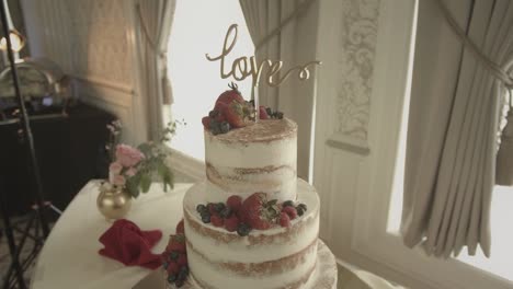 Fresh-fruit-crème-frosting-layered-fine-luxury-wedding-cake-centrepiece-at-marriage-banquet-push-in-left