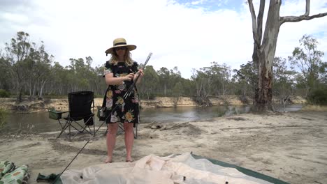 Blonde-woman-packing-up-tent-Australia-camping-pegs-and-poles