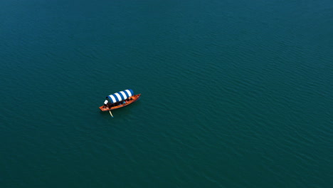 Bird's-Eye-View-Of-A-Man-Paddling-On-A-Pletna-Boat-At-The-Blue-Water-Of-Bled-Lake-In-Slovenia
