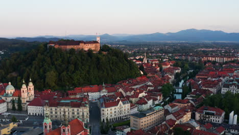 Vista-Aérea-De-Los-Edificios-Medievales-En-La-Orilla-Del-Río-Ljubljanica-Y-El-Castillo-De-Ljubljana-En-Eslovenia