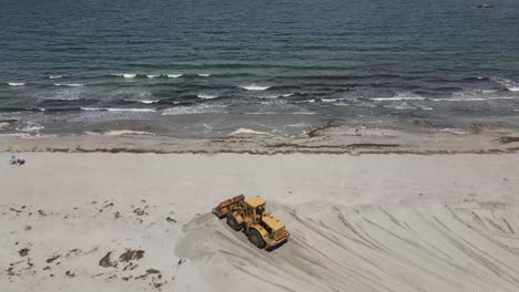 Wheel-Loader-Pushing-And-Reshaping-Sandy-Beach-By-Pacific-Ocean-In-Cohasset,-Massachusetts,-USA