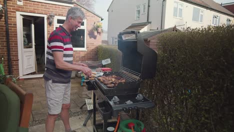 Adult-caucasian-man-having-fun-cooking-meat-on-barbecue-grill-in-home-garden