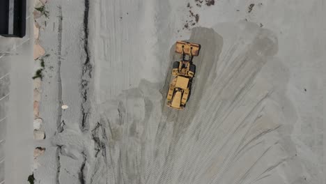 Birds-eye-move-of-aerial-drone-footage-of-two-earth-movers-reshaping-sandy-beach-at-Cohasset,-MA