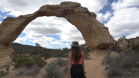 Junge-Fotografin-Nähert-Sich-Natürlichem-Sandsteinbogen,-Shiprock-Navajo-Territorium,-New-Mexico,-USA,-Vollbild-Zeitlupe