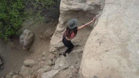 Top-Down-View-of-Young-Female-Hiker-Climbing-on-Steep-Rocky-Cliff-in-Wilderness-of-Navajo-Territory,-New-Mexico,-USA,-Full-Frame-Slow-Motion
