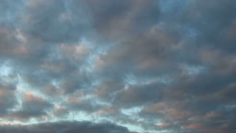 Waving-patterns-of-small-cumulus-clouds-into-different-directions-with-colorful-sunset-and-dark-tones-of-blue-hour
