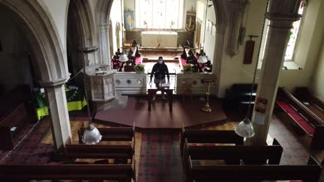 Jib-shot-of-a-vicar-standing-at-the-front-of-an-Empty-church-in-England