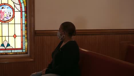 Black-woman-sitting-in-empty-church-gazing-out-window