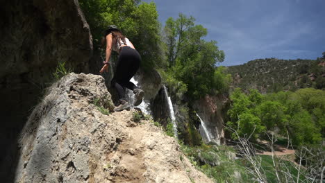 Young-female-photographer-climbing-on-rock-under-Rifle-Falls,-Colorado-USA,-slow-motion