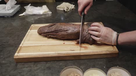 Chef-cuts-freshly-grilled-beef-fillet-on-wooden-cut-board-at-meat-tasting-event