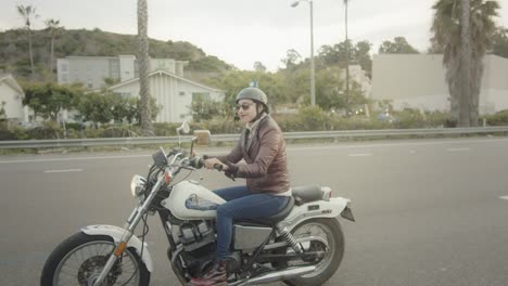Reveal-of-female-biker-who-smiles-at-the-camera-while-driving-her-vintage-motorcycle-in-California