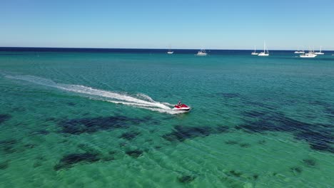 Aerial-view,-water-scooter-sailing-on-turquoise-sea-water-near-australian-coast-on-sunny-summer-day,-orbit-drone-shot