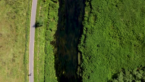 4K-flying-over-the-River-Stour-in-Canterbury-with-a-cyclist-riding-on-the-pathway