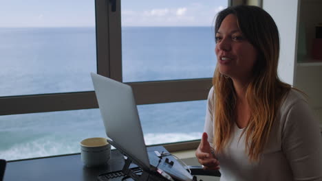 Happy-woman-telling-a-story-while-remote-working-with-a-ocean-view