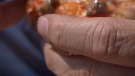 Taking-a-bite-of-fresh-sausage-and-tomato-pizza---close-up