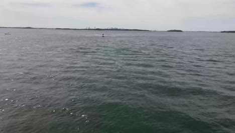 Low-aerial-footage-of-drone-heading-toward-Boston,-MA,-intercepting-a-buoy-sea-marker