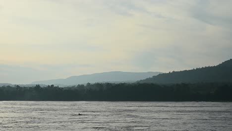 Un-Barco-Visto-Cruzando-Diagonalmente-El-Río-Mekong-Desde-El-Lado-De-Tailandia-A-Laos-Durante-La-Primera-Parte-Del-Día