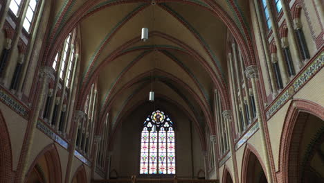 Arch-Shaped-Stained-Glass-Panel-And-The-Rib-Vault-Ceiling-At-Gouwekerk-Church-In-Gouda,-Netherlands