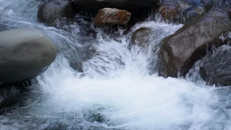 Detail-shot:-a-river,-with-water-running-and-falling-over-levigated-rocks