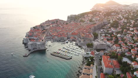 Toma-Aérea-Sobre-El-Casco-Antiguo-De-Dubrovnik-Durante-La-Puesta-De-Sol-En-La-Costa-Del-Mar-Adriático,-Dalmacia,-Croacia---Popular-Destino-Turístico