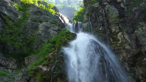 Water-stream-falling-from-rocks-on-mountains-slope-and-green-vegetation-in-Theth,-Albania