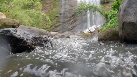 A-low-angle-view-of-the-water-at-the-bottom-of-a-waterfall-in-the-jungle