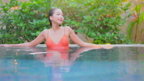 Portrait-of-Asian-Woman-relaxing-inside-swimming-pool-of-a-luxury-tropical-hotel-in-Bali