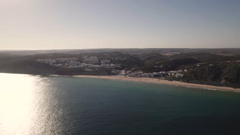 High-aerial-above-the-atlantic-ocean-facing-the-coastline-of-Salema,-Portugal