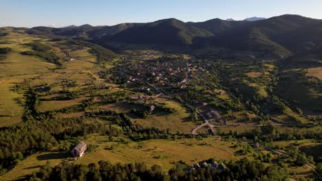 Mountain-village-of-Voskopoja-at-twilight-golden-hour,-surrounded-by-green-meadows-and-pine-forests