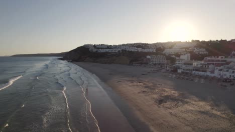 Panoramic-aerial-view-looking-at-the-sunsetting-in-Praia-da-Salema-beach-Algarve-Portugal