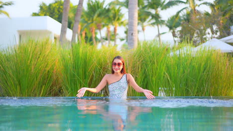 A-pretty-woman-has-fun-by-splashing-the-water-in-a-resort-swimming-pool
