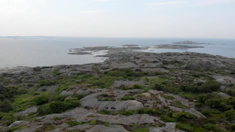 Aerial-drone-fly's-forwards-over-a-small-rocky-island-covered-with-ocean-crashing-below-in-Hönö-Island,-gothenburg-archipelago