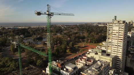 Aerial-orbit-shot-of-cranes-on-construction-site-in-Buenos-Aires-during-sunset