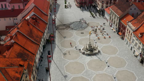 Aerial-View-Of-Few-People-At-Main-Square-With-Plague-Column-Monument-In-Slovenia