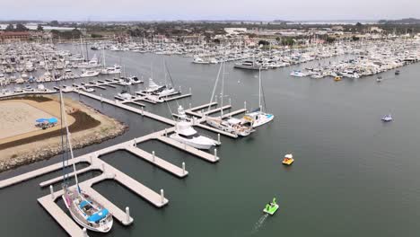 Aerial-rising,-Ventura-Harbor-over-boats-calm-water-on-cloudy-day