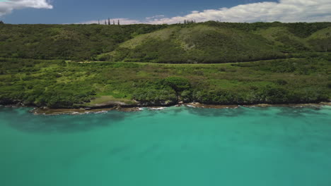 Aerial-push-in-toward-small-cove-from-wide-angle-of-view-from-Isle-of-Pines,-New-Caledonia